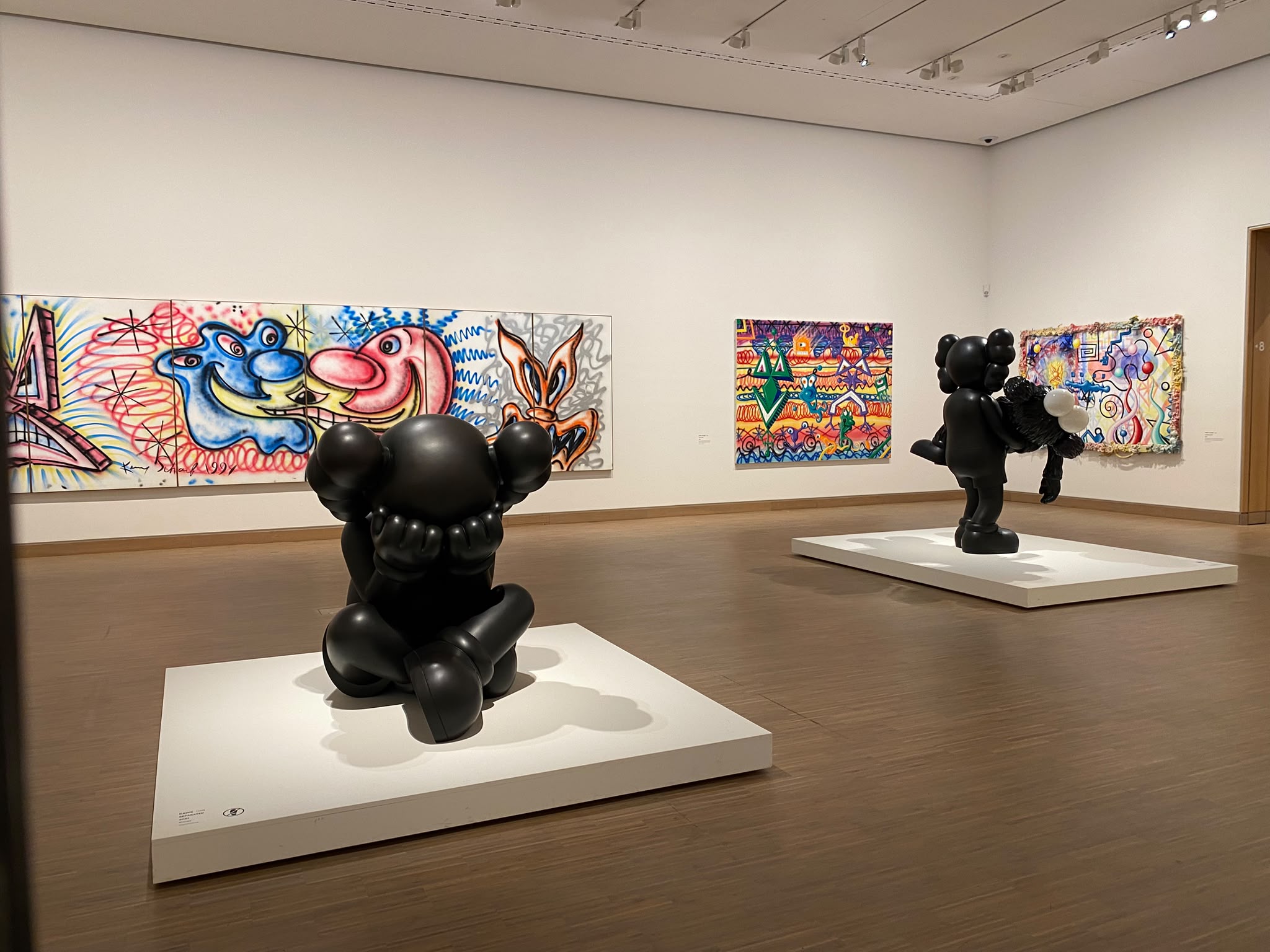 Two black KAWS sculptures among paintings at Albertina Modern.